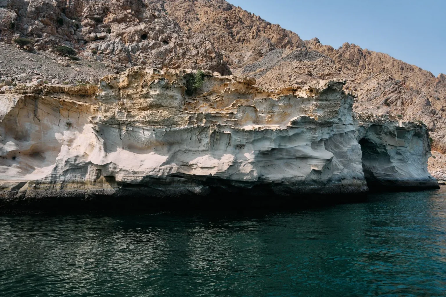 Stunning view of rocky cliffs along the Musandam, Oman coastline during a sunny day.