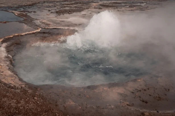 An active geyser erupting in the Icelandic landscape, captured in vivid detail.