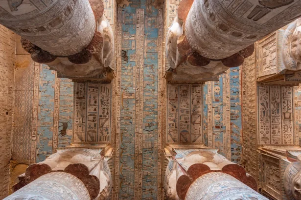 Detailed view of a richly decorated ancient Egyptian temple ceiling and columns.