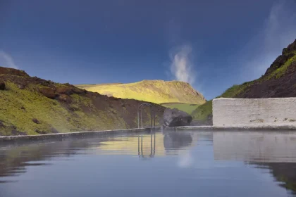 Relaxing hot spring pool in the scenic Icelandic mountains with clear blue skies.