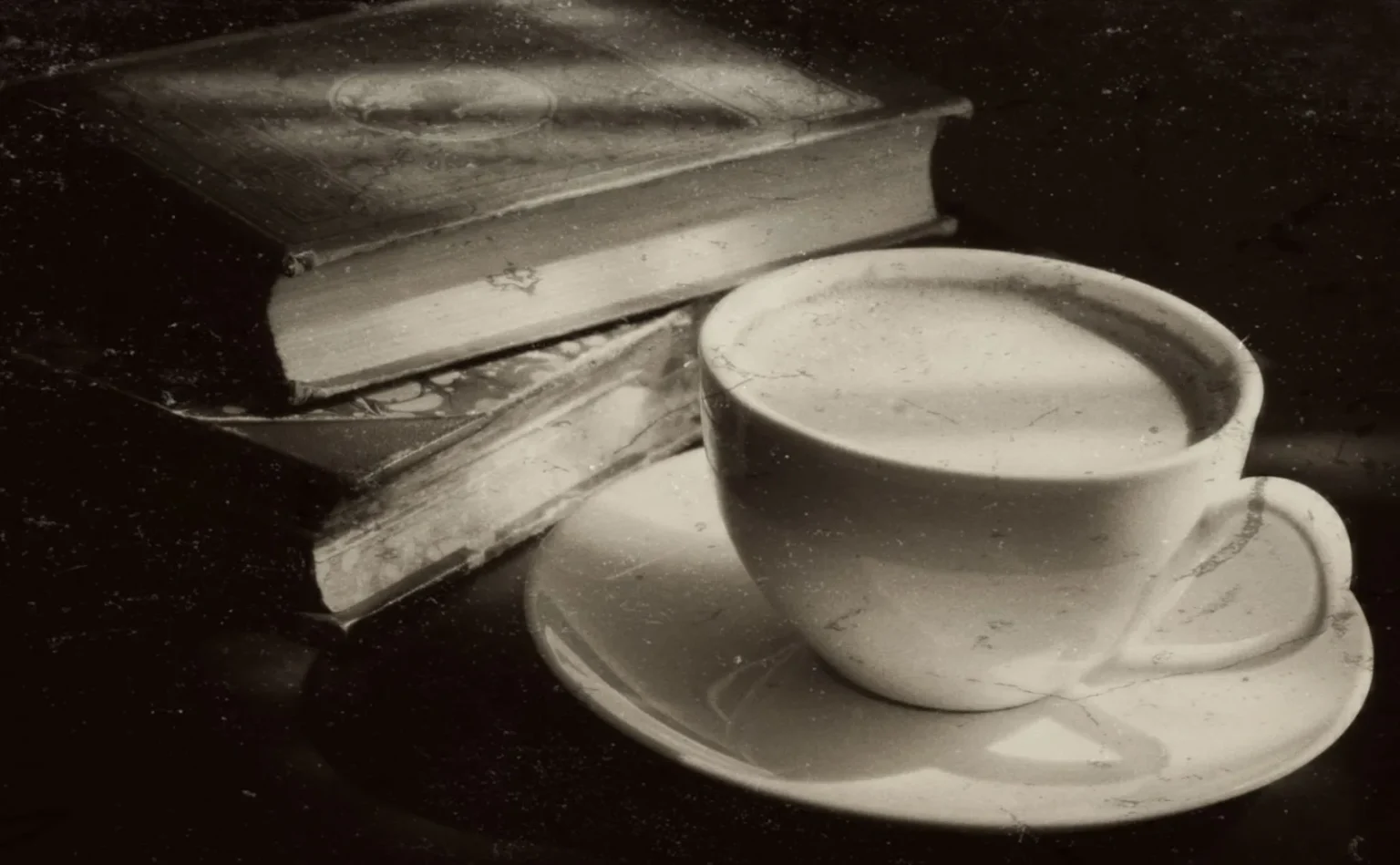 A vintage-style black-and-white image of a coffee cup with books, exuding a classic and timeless ambiance.