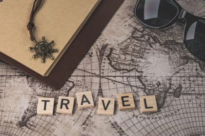 Close-up of travel items including map, helm pendant, notebook, and sunglasses.