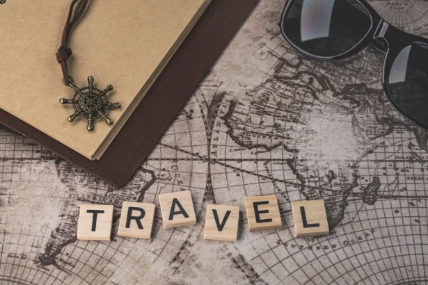 Close-up of travel items including map, helm pendant, notebook, and sunglasses.
