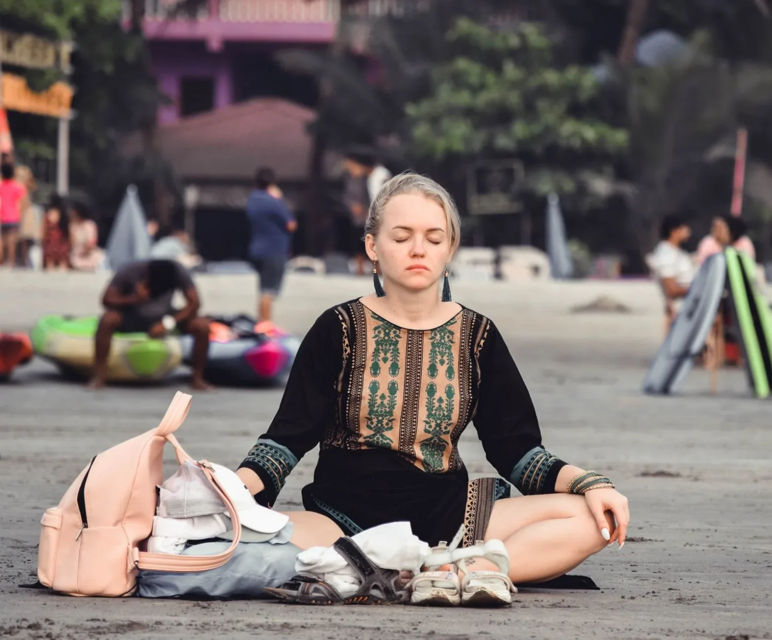 A woman peacefully meditates on Arambol Beach in Goa, India, surrounded by the natural beauty of the coastline.