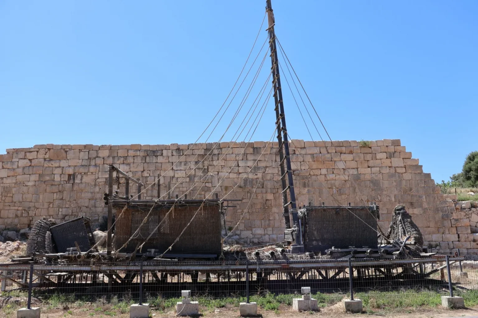 Ancient shipwreck display at archaeological site in Antalya against stone wall.