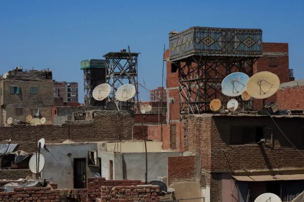 Cairo's rooftops showcase satellite dishes and urban structures under a clear sky.