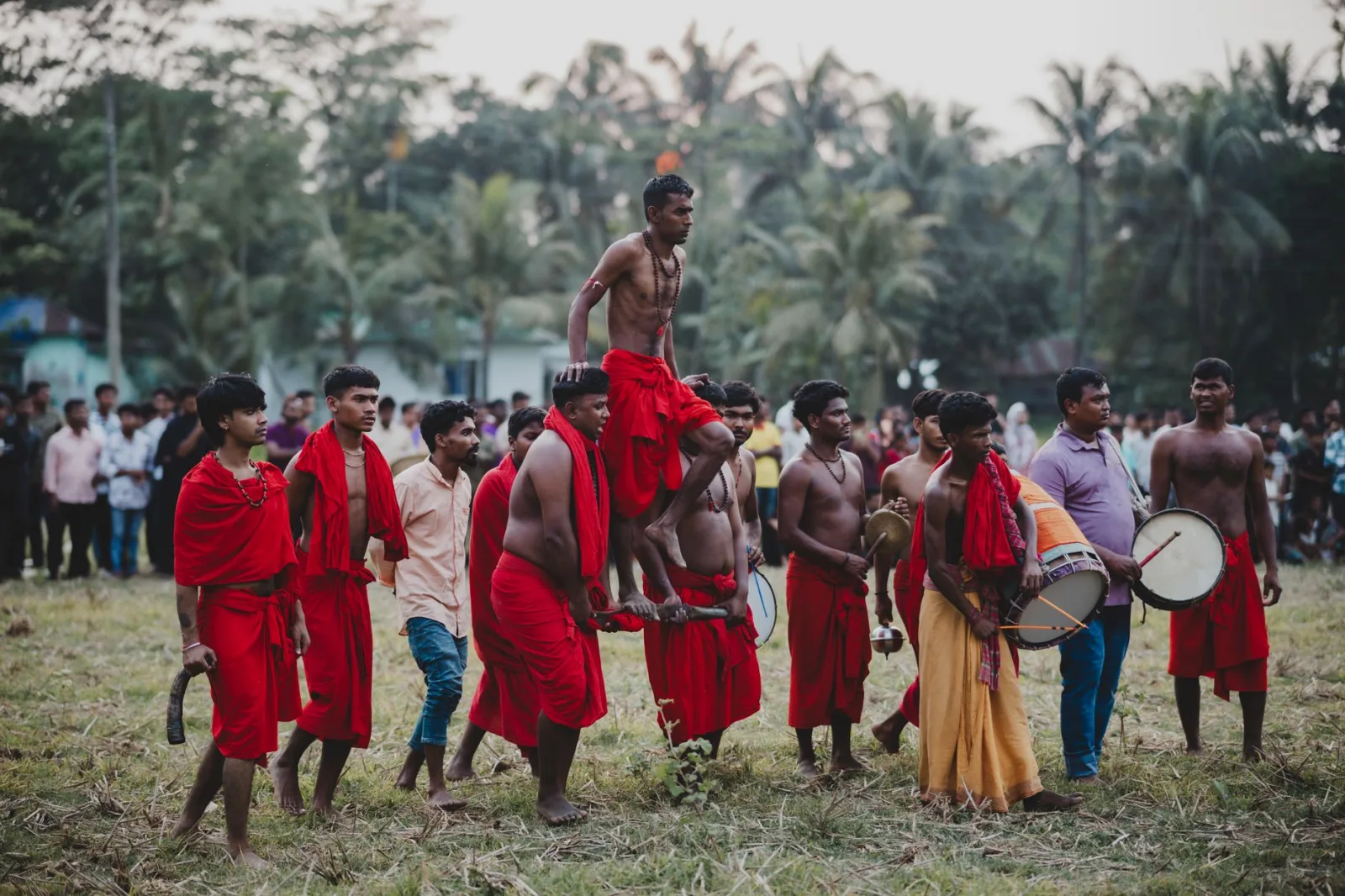 Group of men in traditional attire performing at a cultural festival outdoors.