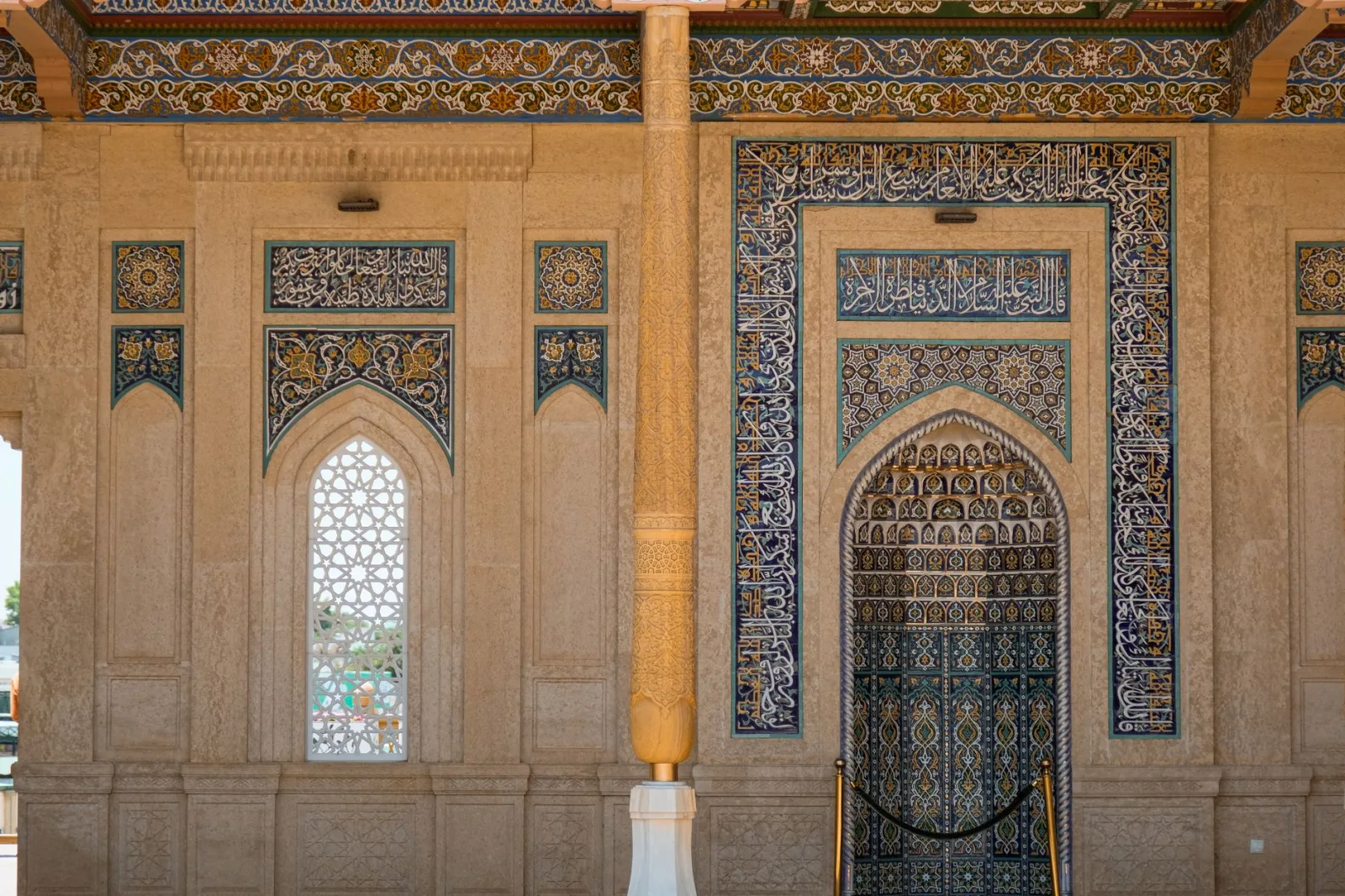 Detailed view of Islamic architecture featuring ornate mosaic and Arabic calligraphy.