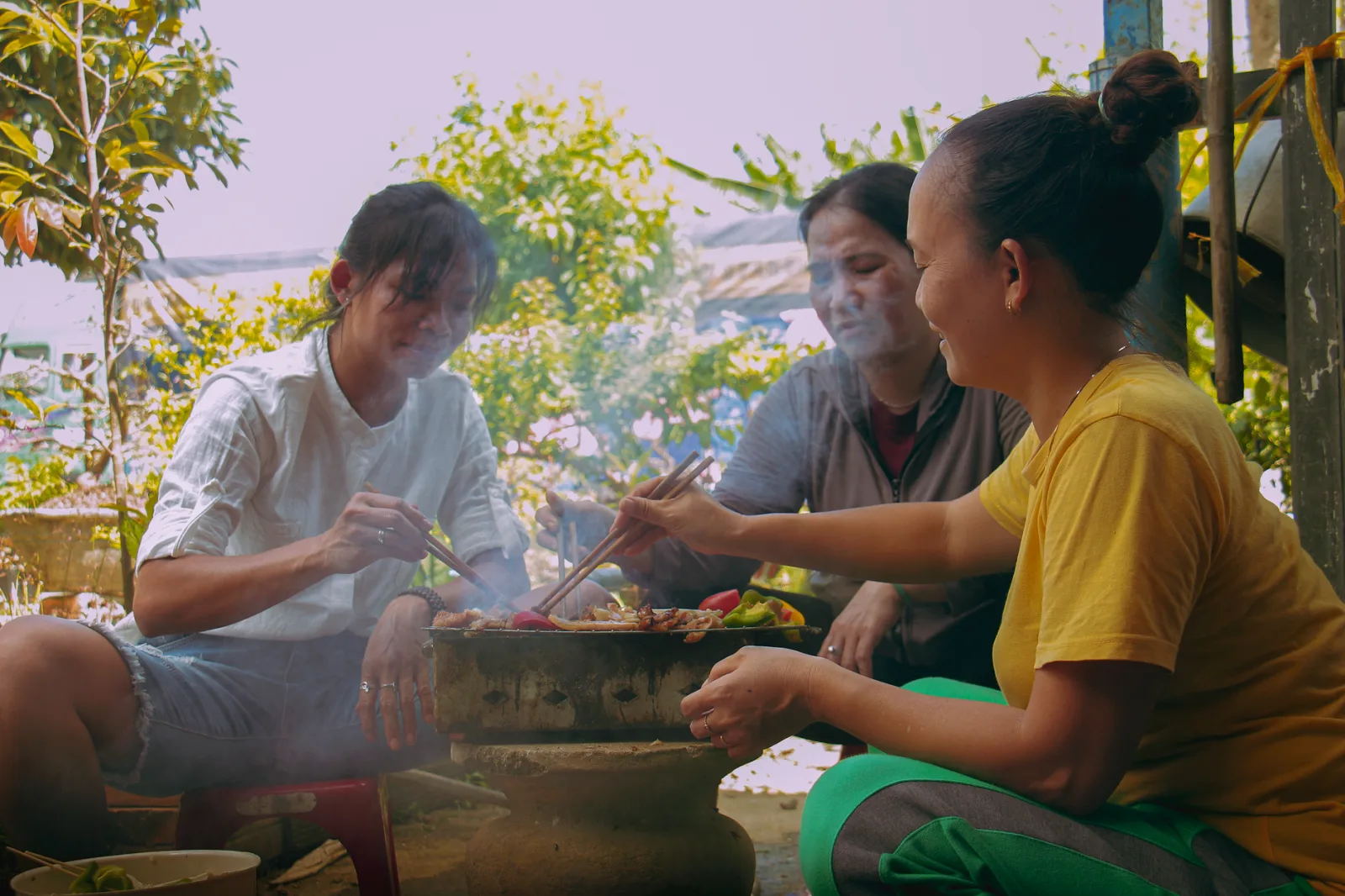 A family enjoys a traditional outdoor barbecue meal together, embracing culture and togetherness.