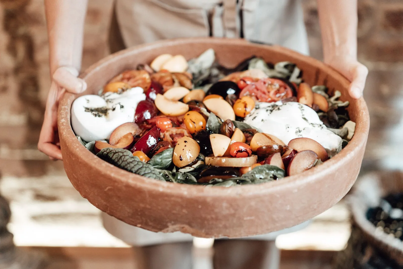 A vibrant rustic salad featuring fresh fruits, greens, and cheese in a wooden bowl, perfect for summer meals.