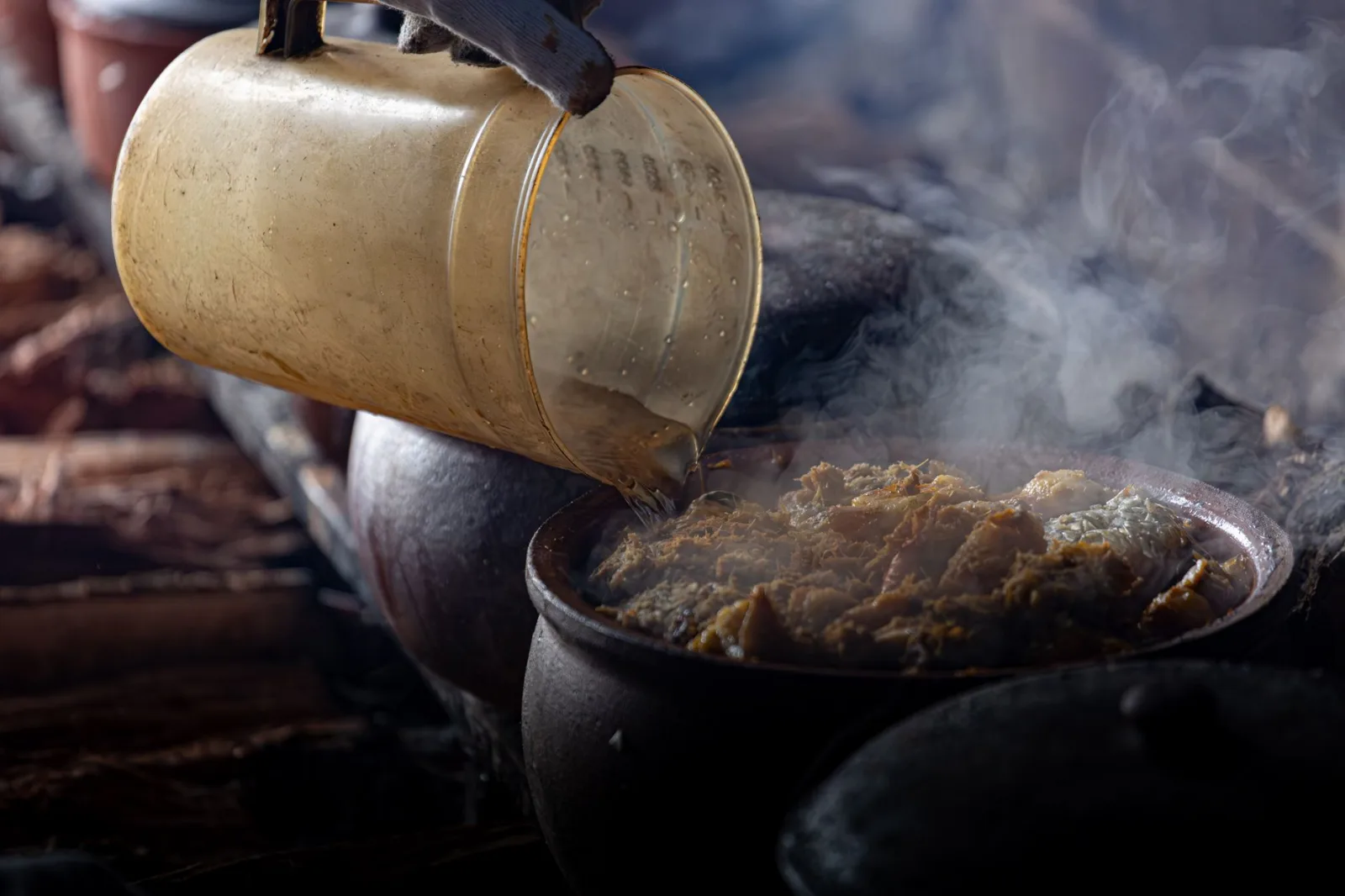 A steaming clay pot in a Vietnamese kitchen with traditional cooking methods.