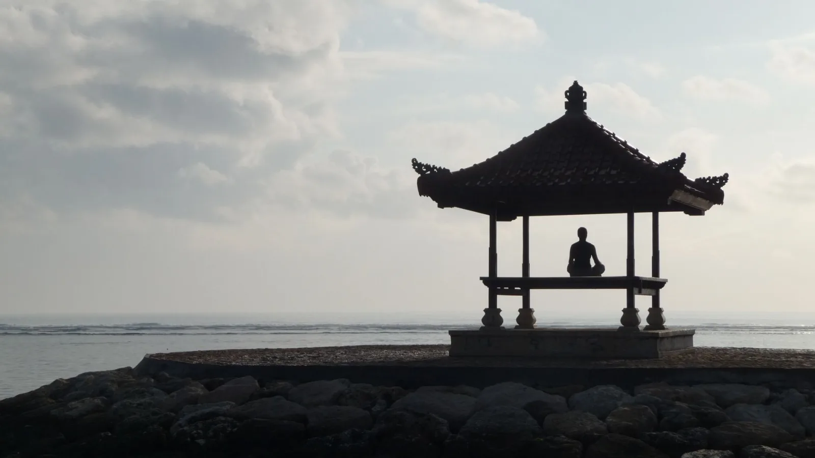 Silhouette of a person meditating in a gazebo by the sea in Balikpapan, Indonesia.