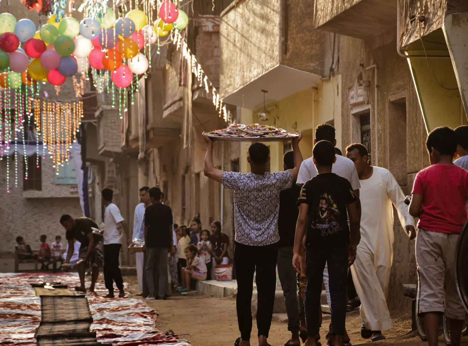 Vibrant street festival with balloons and people celebrating in traditional attire.