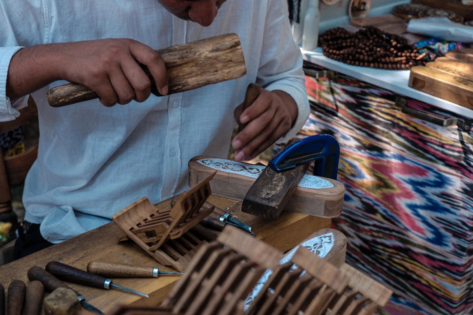 Skilled Uzbek artisan handcrafting wood carvings using traditional tools, showcasing cultural craftsmanship.