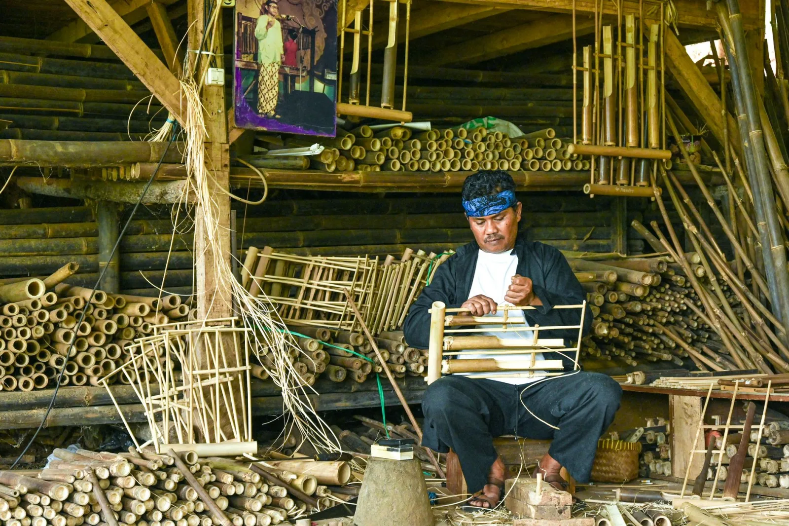 Traditional craftsman skillfully creating bamboo instruments in Bandung, Indonesia.