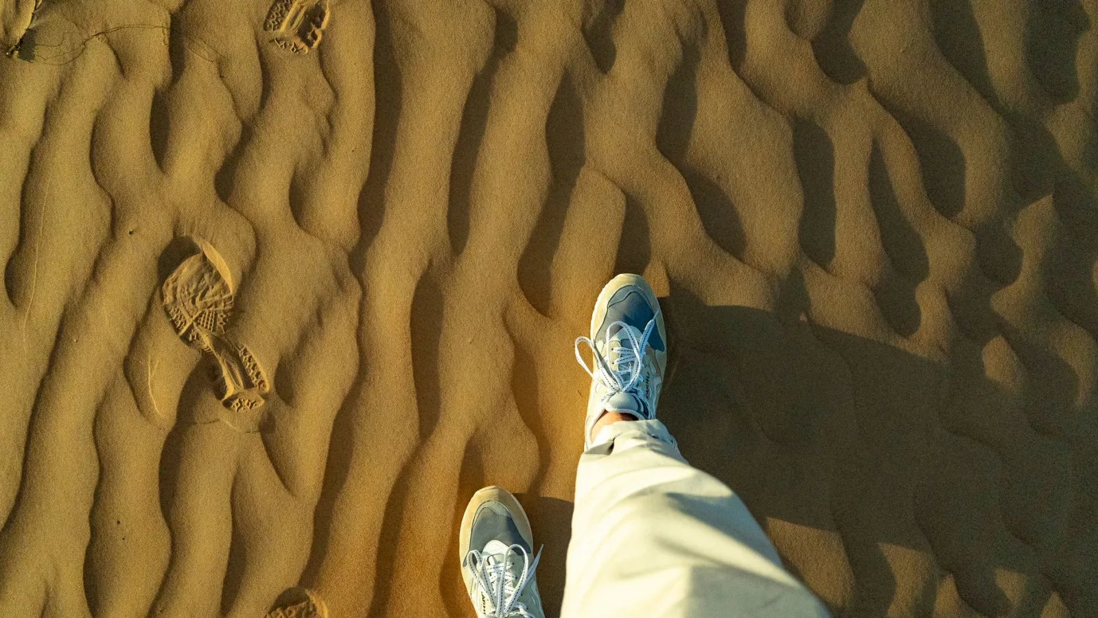 Explore the serene patterns of Oman's desert sands and footprints on an adventurous journey.