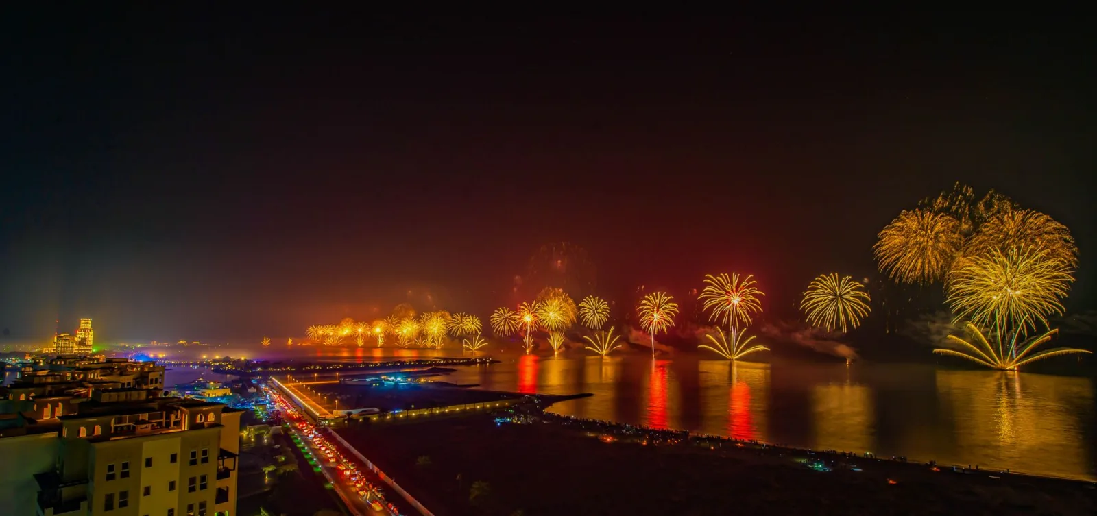 A breathtaking fireworks display over Ras Al Khaimah cityscape, reflecting on water.