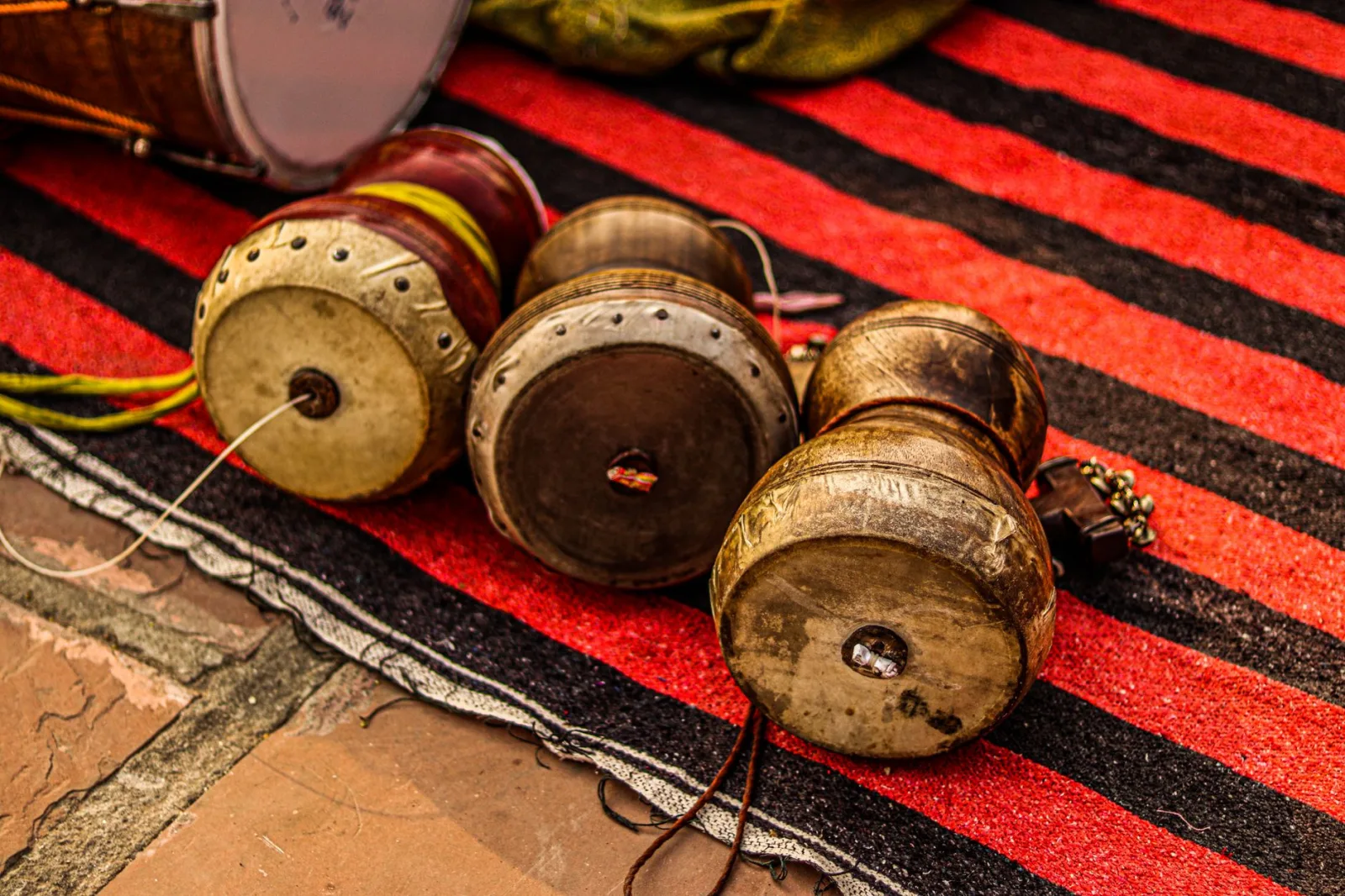 Close-up view of traditional Indian dhol drums placed on a vibrant striped rug, showcasing musical culture.