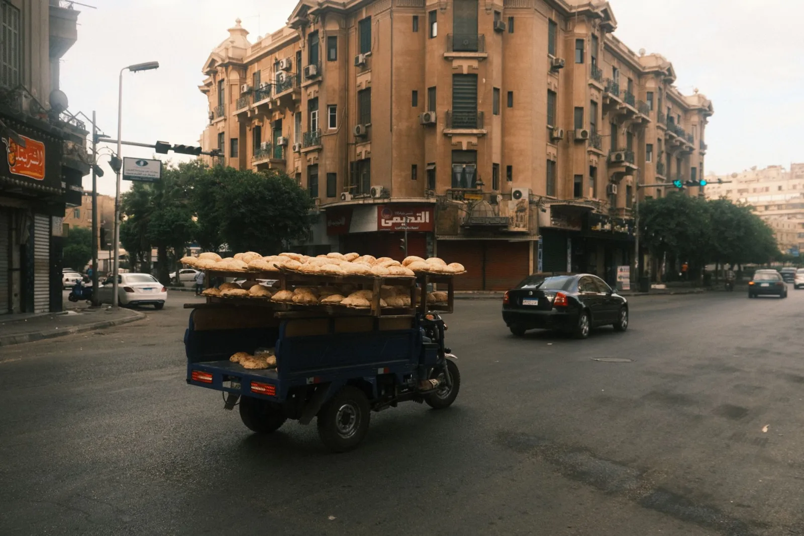 A bread vendor on a motorcycle cart travels through a bustling Cairo street.