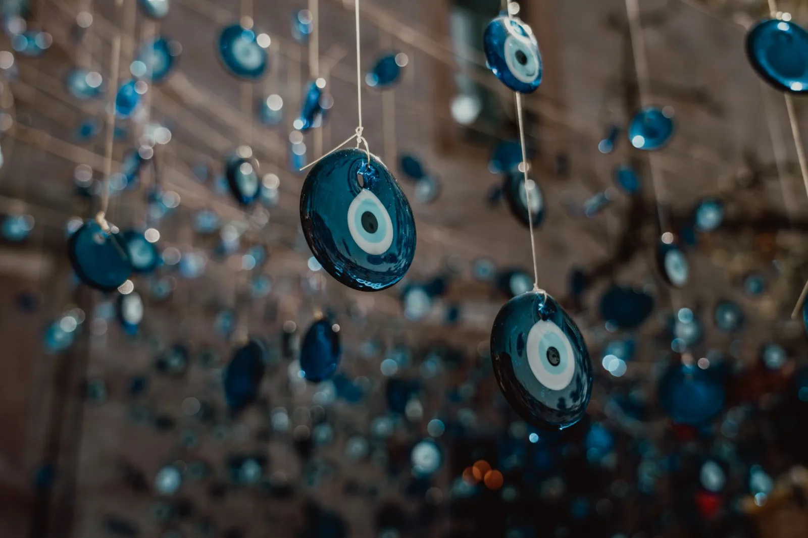 Close-up of numerous blue evil eye charms hanging on strings, capturing tradition and decoration.