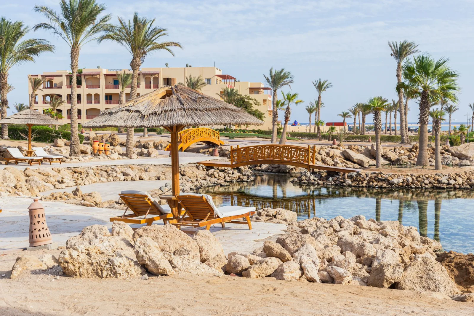 Peaceful resort setting in Safaga, Egypt, featuring palm trees, a lagoon, and sun loungers.