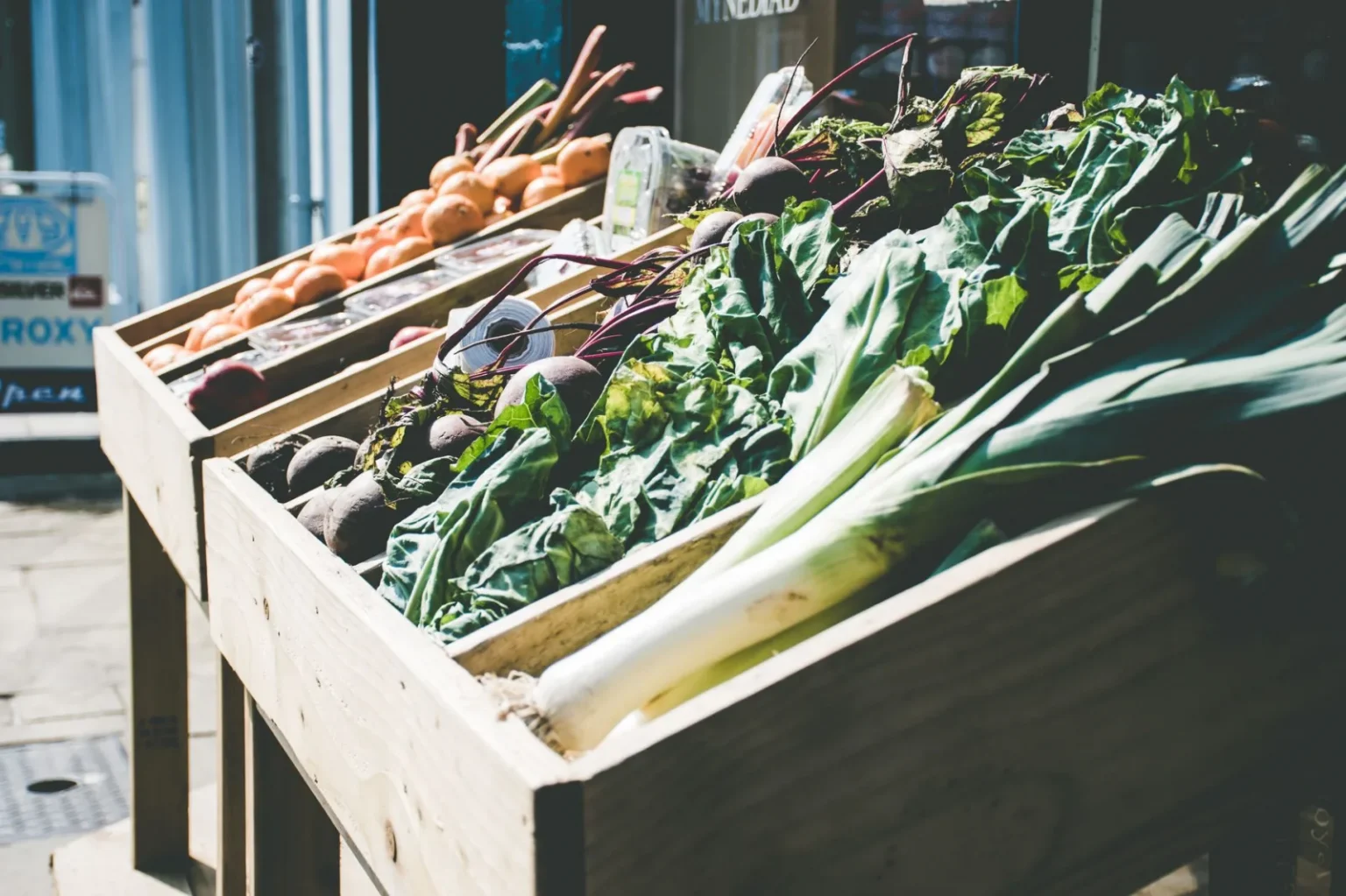 An array of fresh vegetables at an outdoor market stall, showcasing green leafy produce.