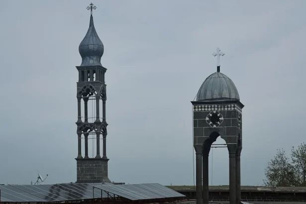 Ancient church towers juxtaposed with modern solar panels under a cloudy sky.
