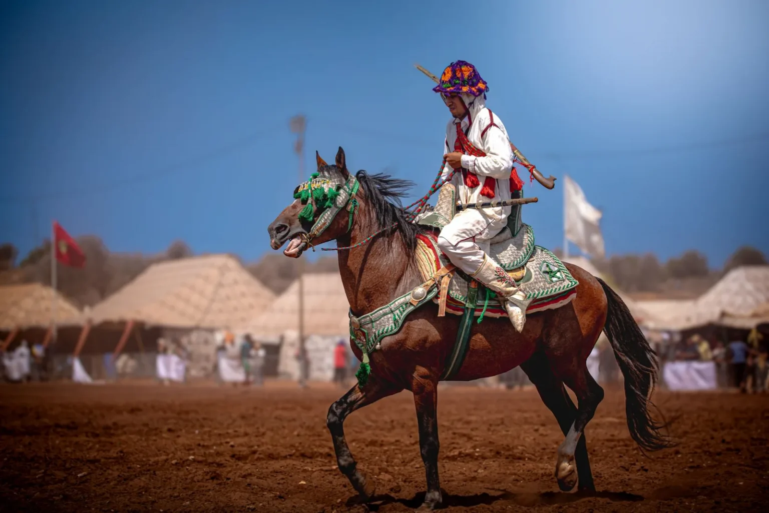 A Moroccan horseman in traditional attire participates in a cultural festival, showcasing national heritage.