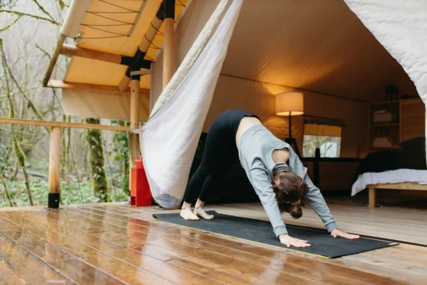 A woman practicing yoga outdoors in a glamping tent, promoting wellness and self-care.
