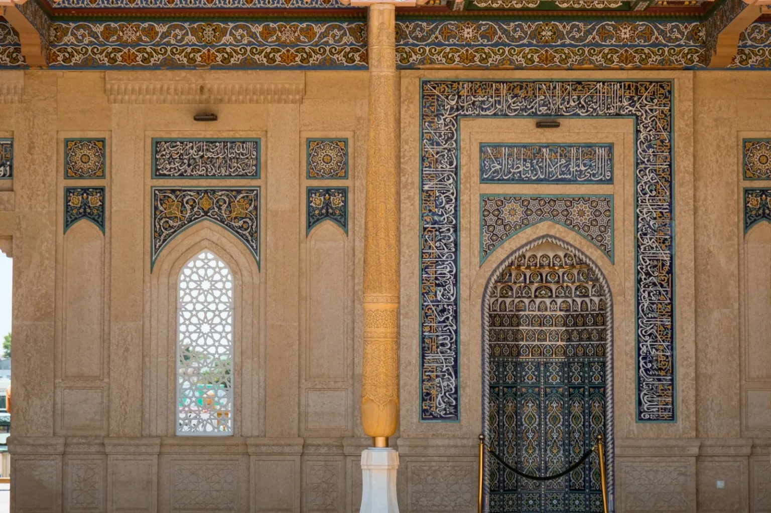 Detailed view of Islamic architecture featuring ornate mosaic and Arabic calligraphy.
