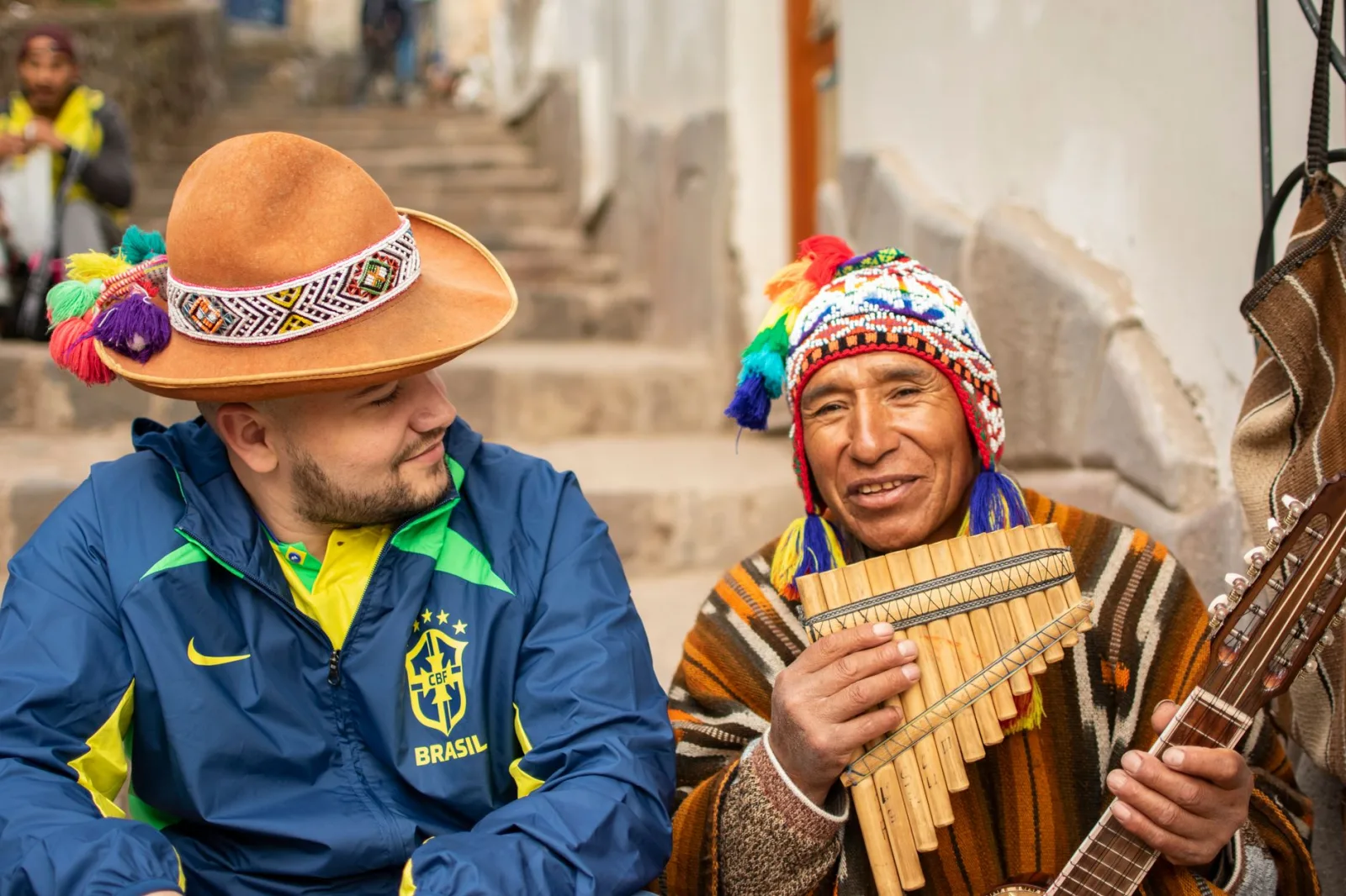 Two men in traditional clothing share a moment of music and friendship in Cusco, Peru.