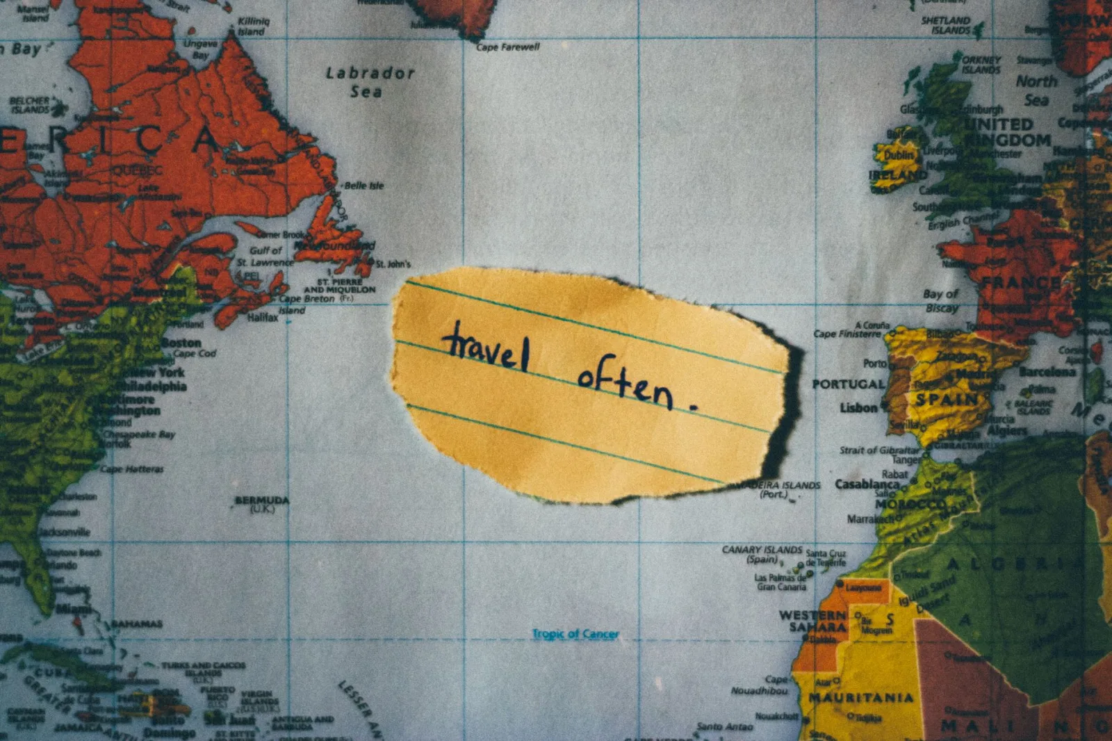 A motivating note 'travel often' placed over a colorful world map, inspiring exploration.