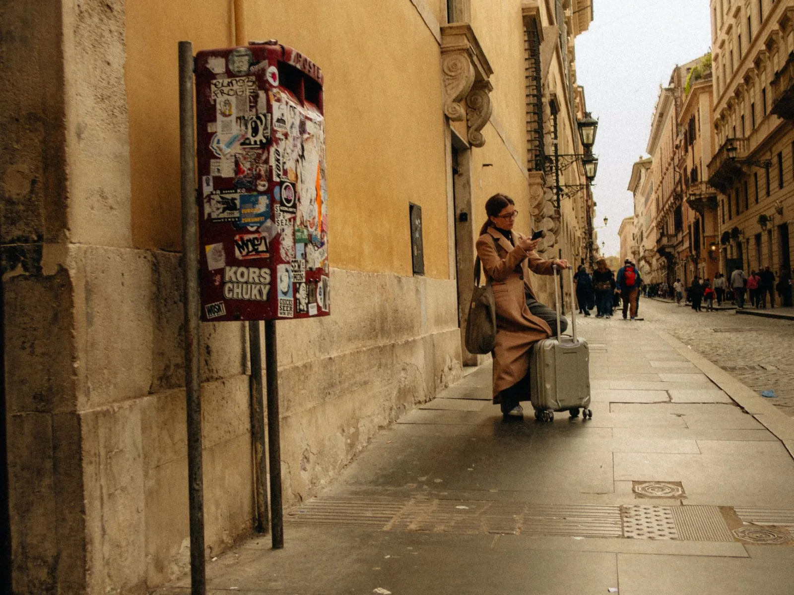 A person with luggage in a narrow, graffiti-decorated alley, highlighting urban travel.