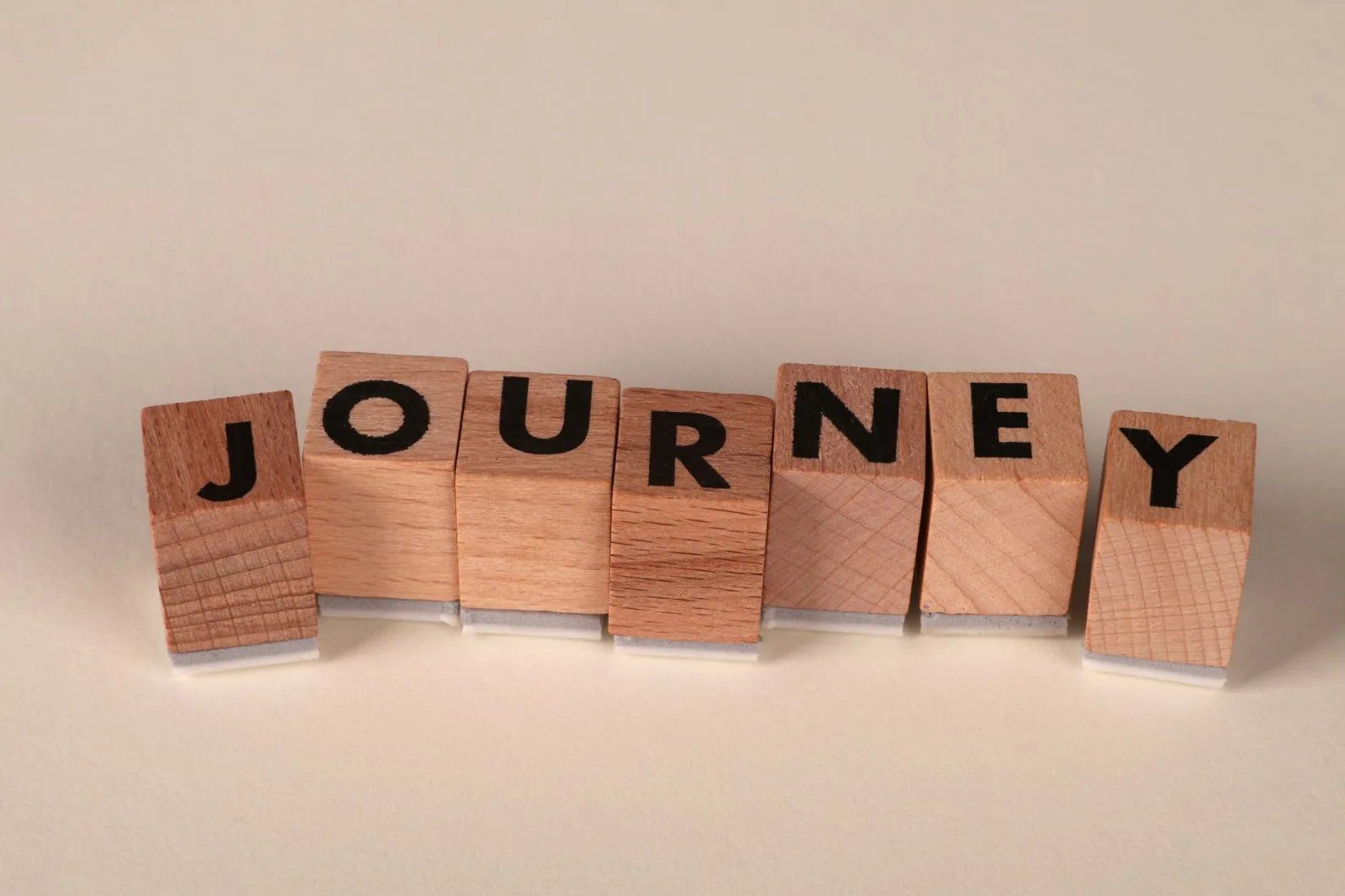 Wooden blocks arranged to spell 'Journey' on a table, symbolizing adventure or progress.