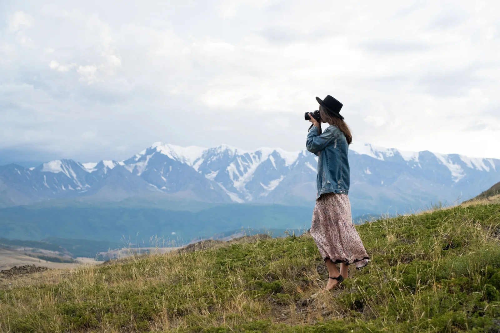 A woman capturing the majestic mountain view with her camera outdoors.