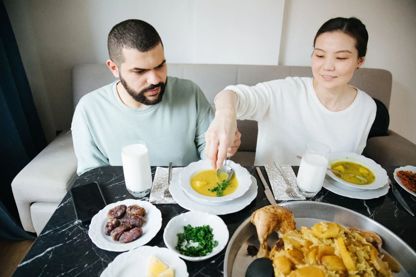 A couple sharing a traditional meal indoors, enjoying dishes like soup and maqluba in Istanbul.
