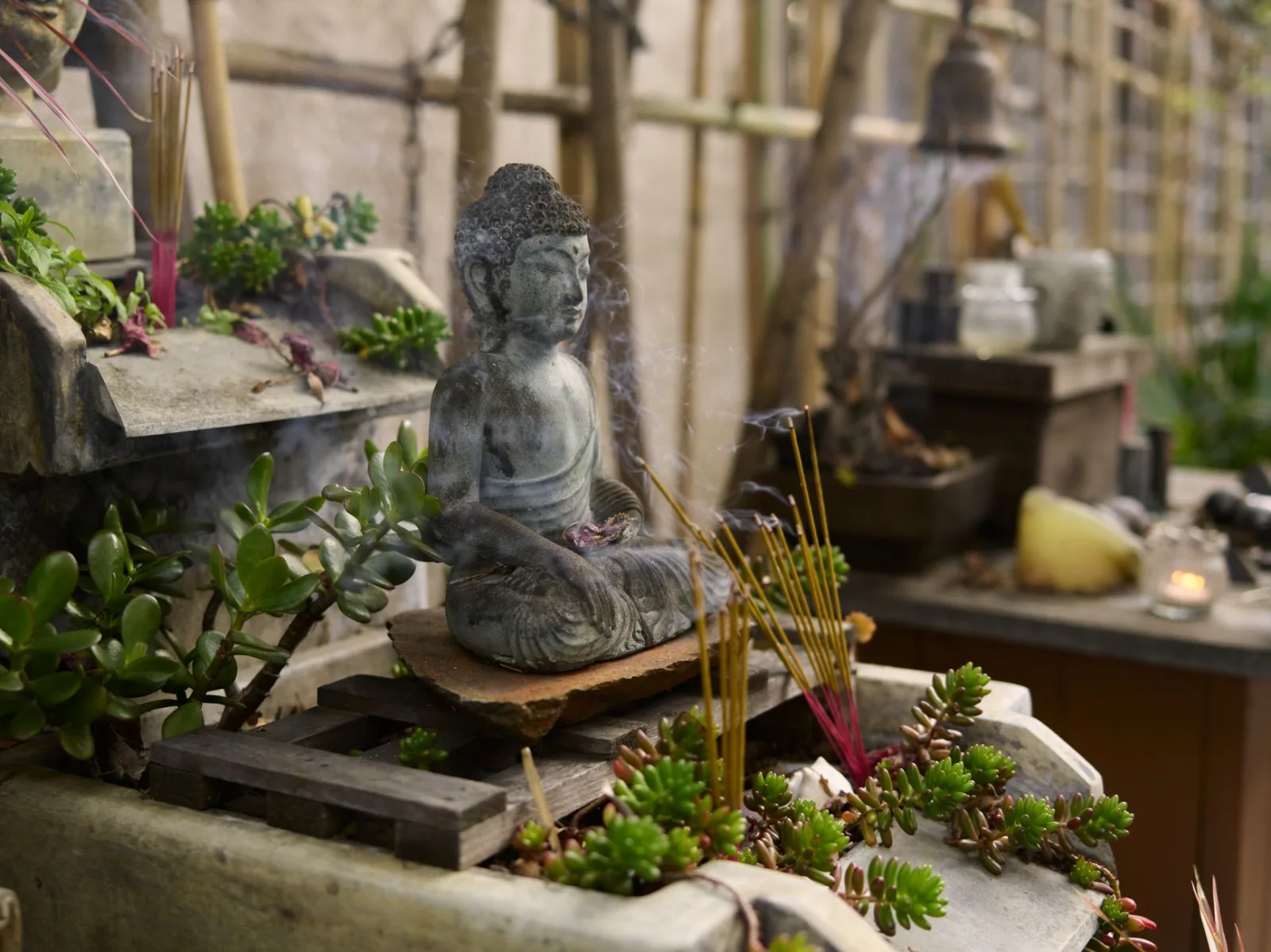 Serene Buddha statue surrounded by incense and plants. Perfect for spiritual themes.