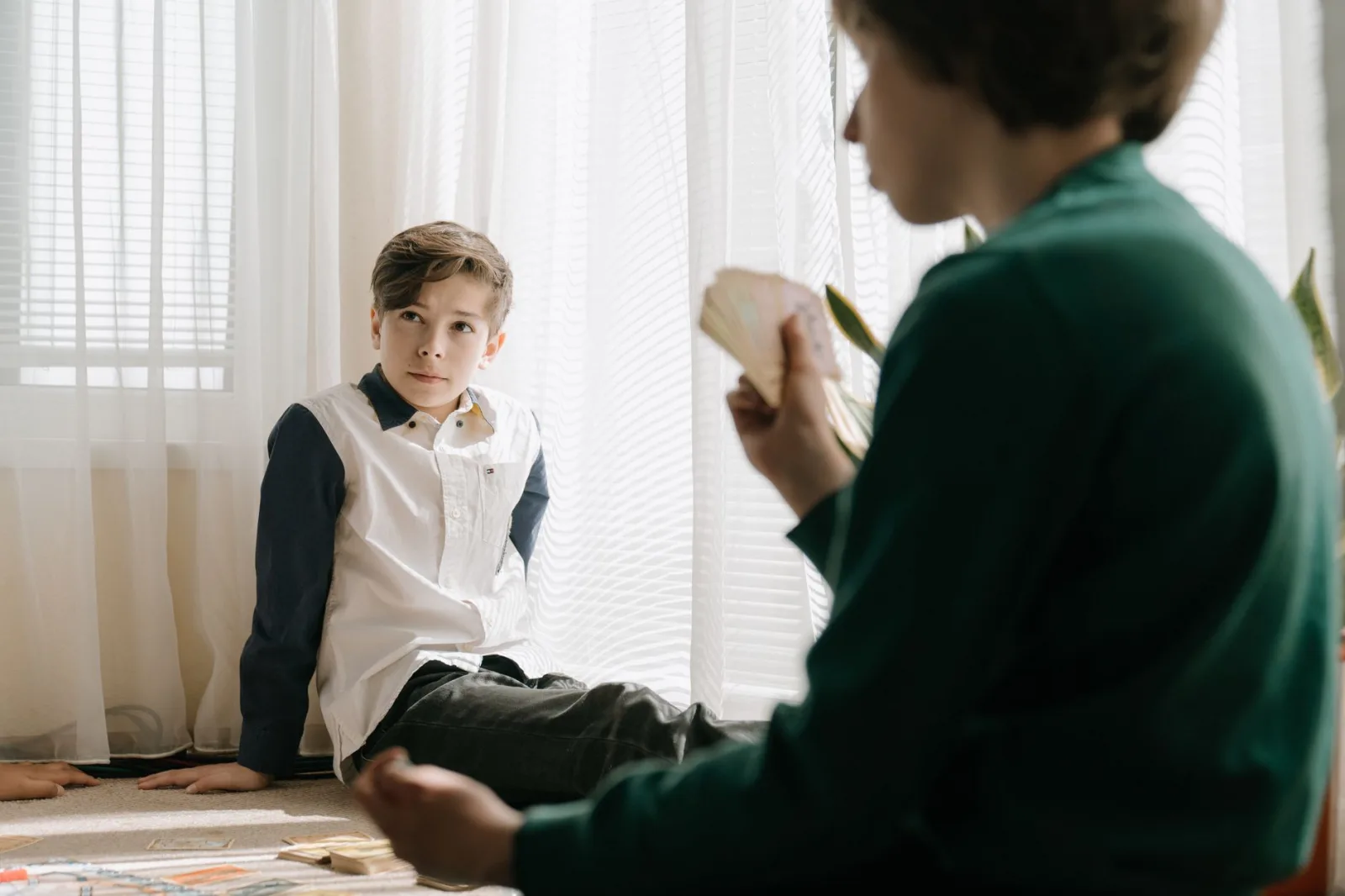 Two kids engaging in a card game indoors, enjoying leisure time and strategic gameplay.
