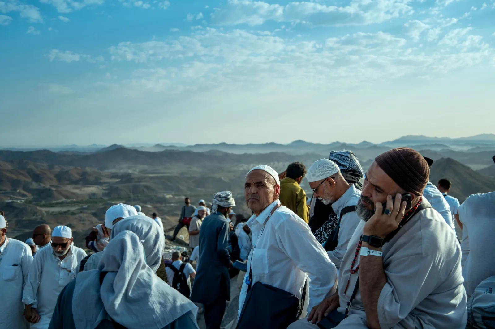 Large group of pilgrims gathering on a mountain in Makkah, Saudi Arabia during Hajj pilgrimage.