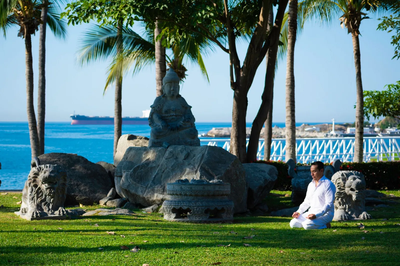 Man meditating in a serene tropical garden by the sea, embracing mindfulness.