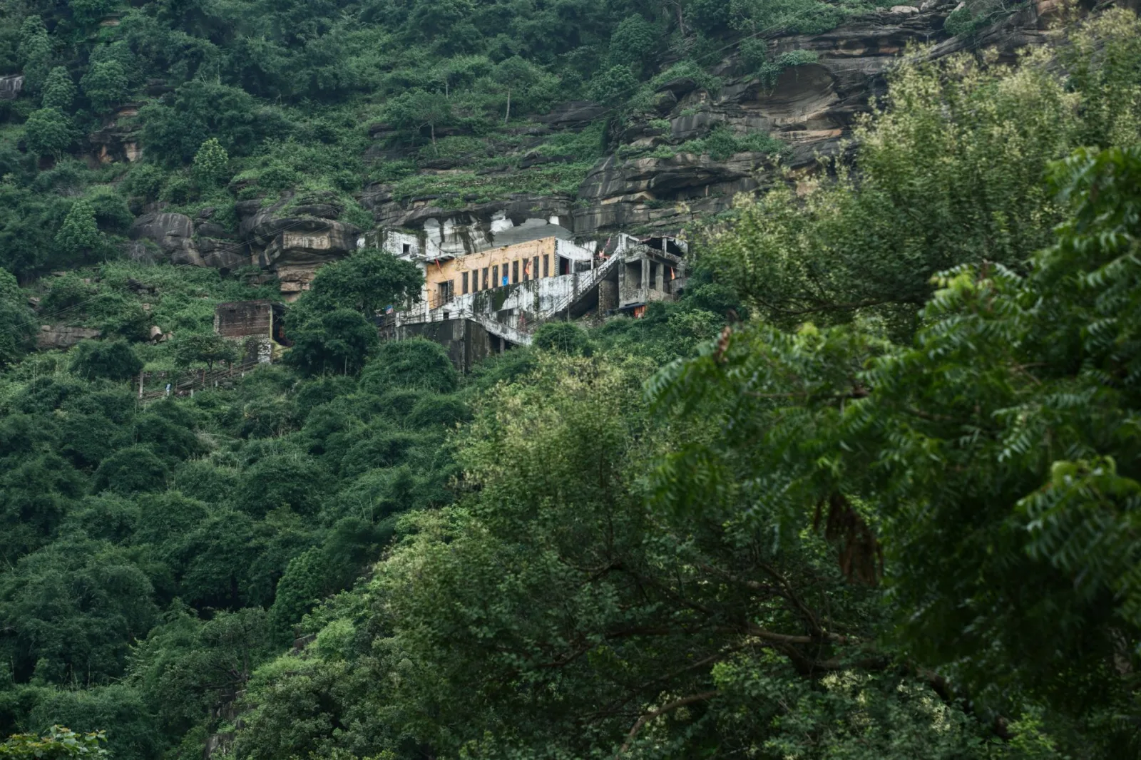 A hidden temple nestled in the lush greenery and rocky terrain of Chitrakoot, India, during summer.