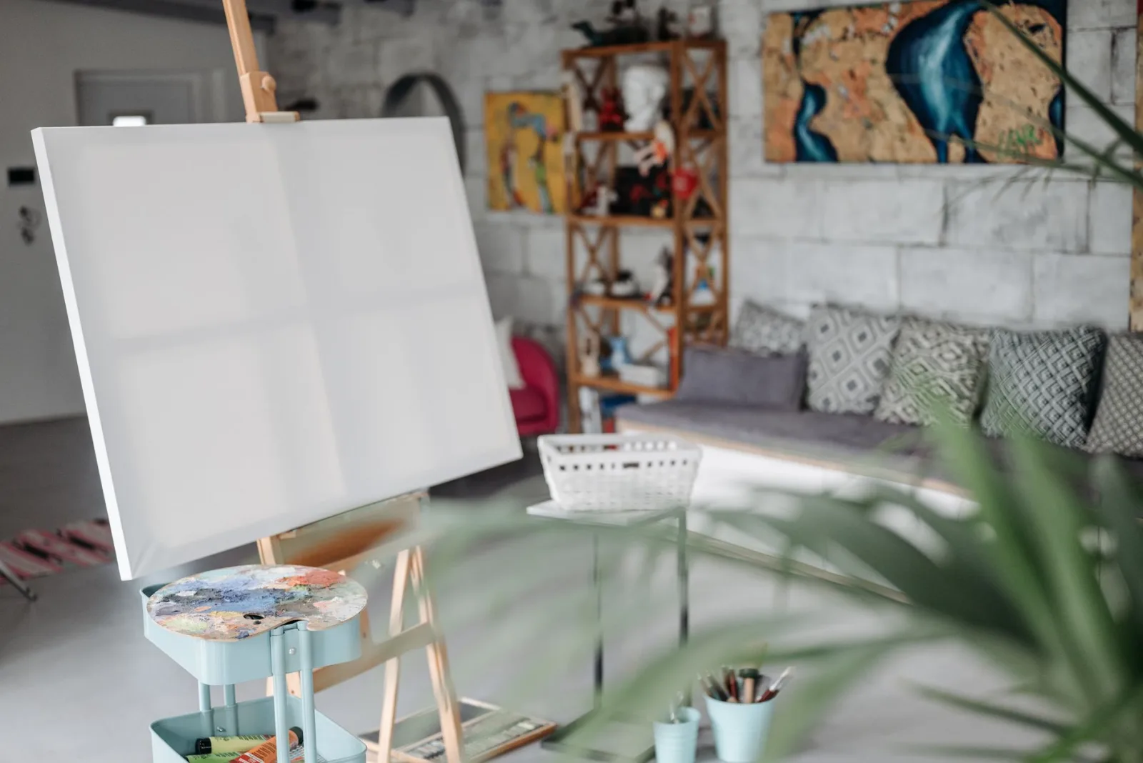 A cozy art studio with a blank canvas on an easel and colorful decor.