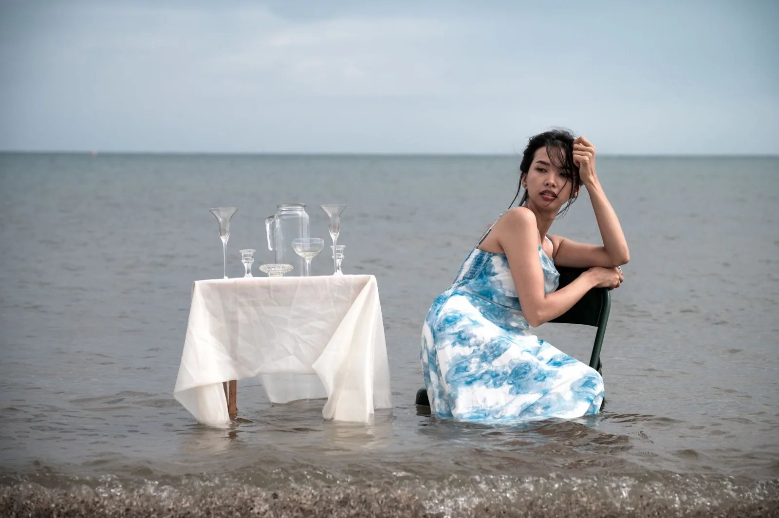 Artistic photo of a woman posing elegantly by a waterfront table in Chicago.