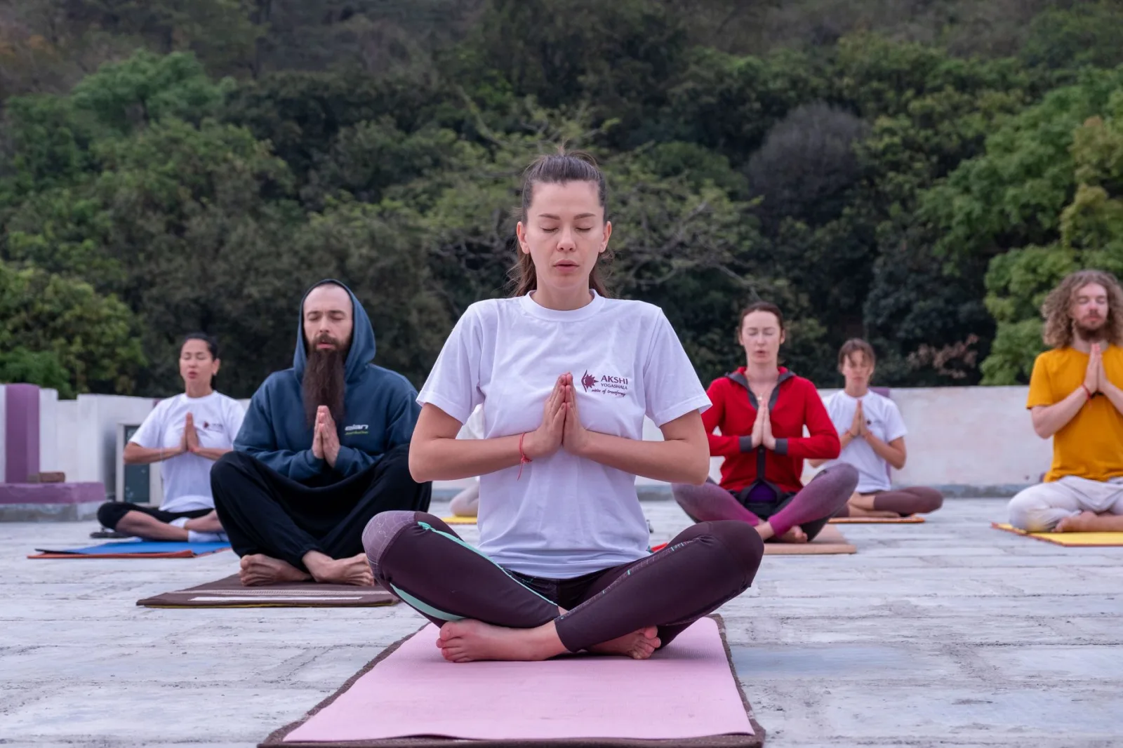 A diverse group practicing meditation outdoors in a serene environment.