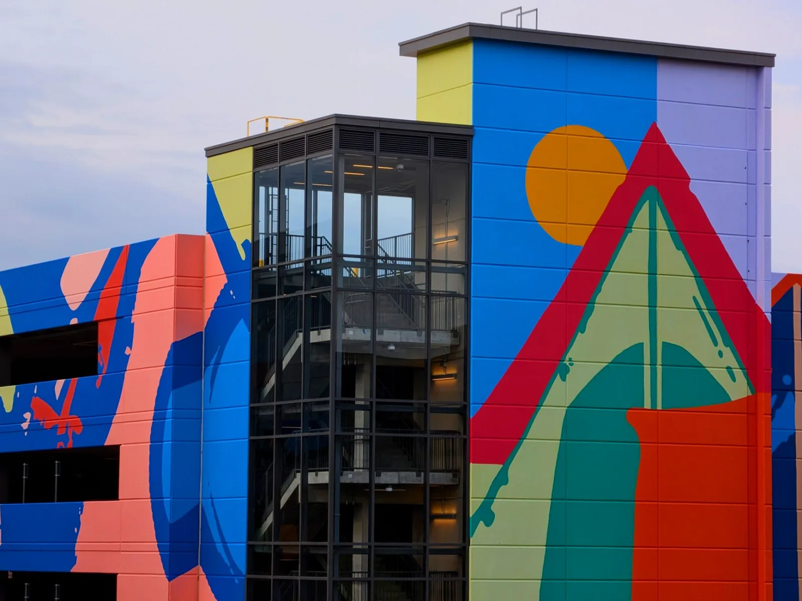 Bright abstract mural on contemporary building exterior with blue, red, and orange hues.