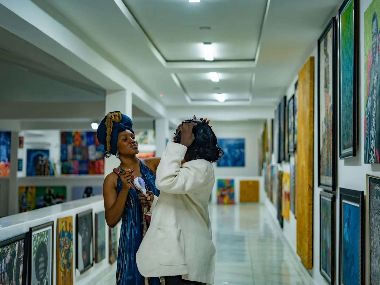 Two adults interacting in a vibrant art gallery filled with colorful paintings.