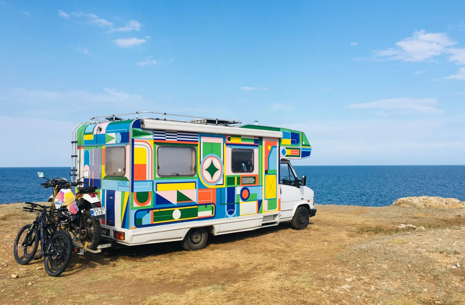 Vibrant camper parked by the sea in Tyulenovo, Bulgaria, under a clear sky.