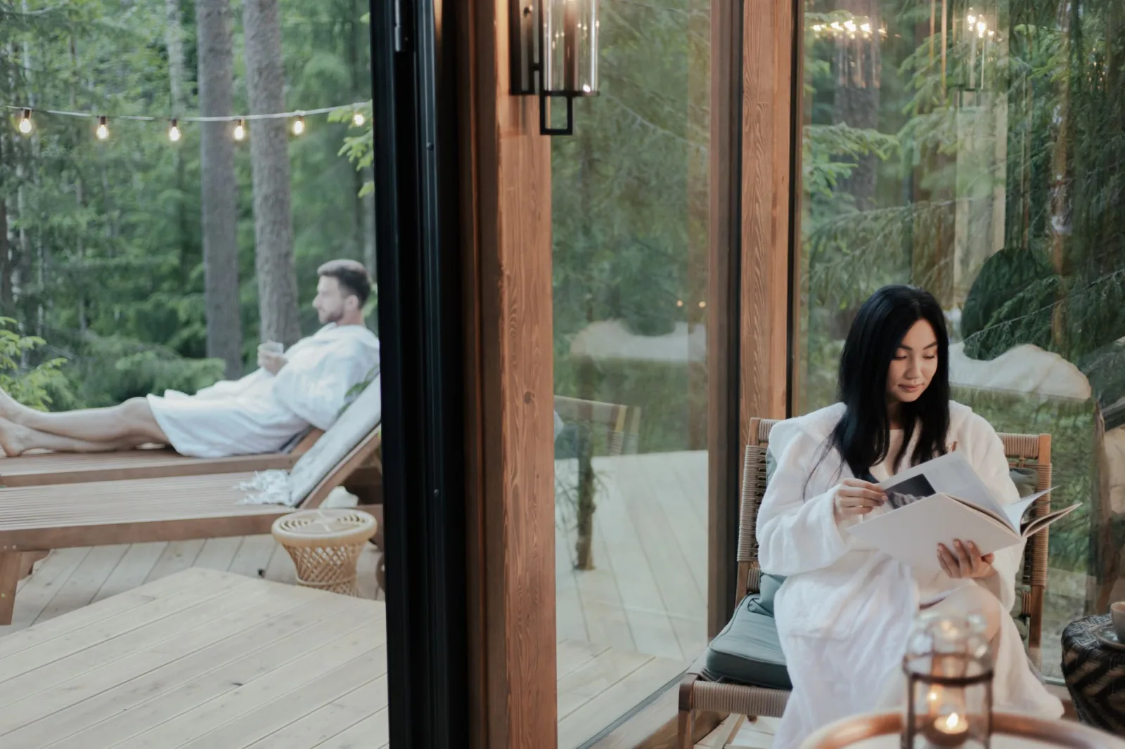 Couple enjoying relaxation in a forest retreat, reading and lounging outdoors.
