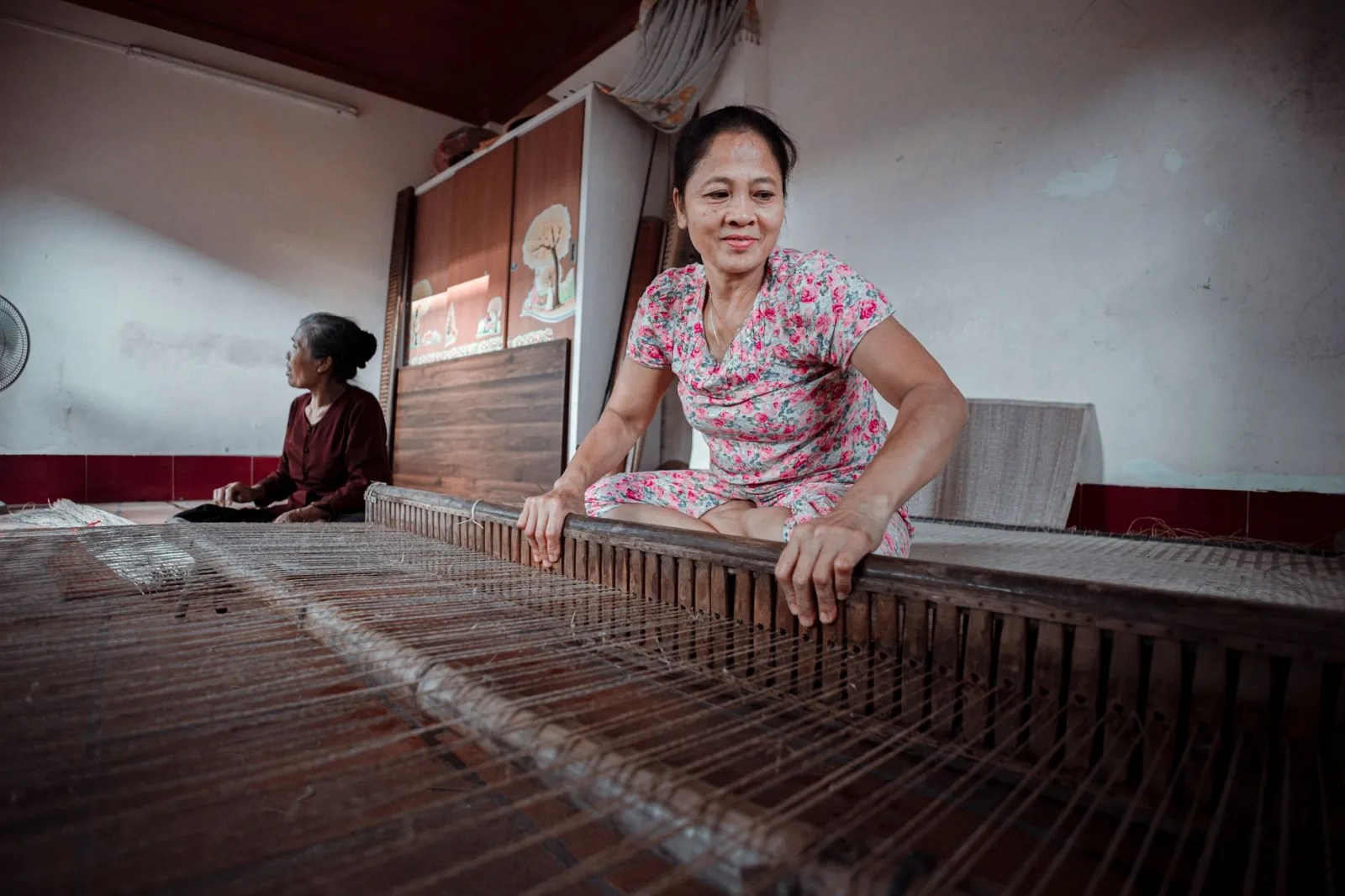 Women skillfully weaving on a traditional loom in an indoor setting.