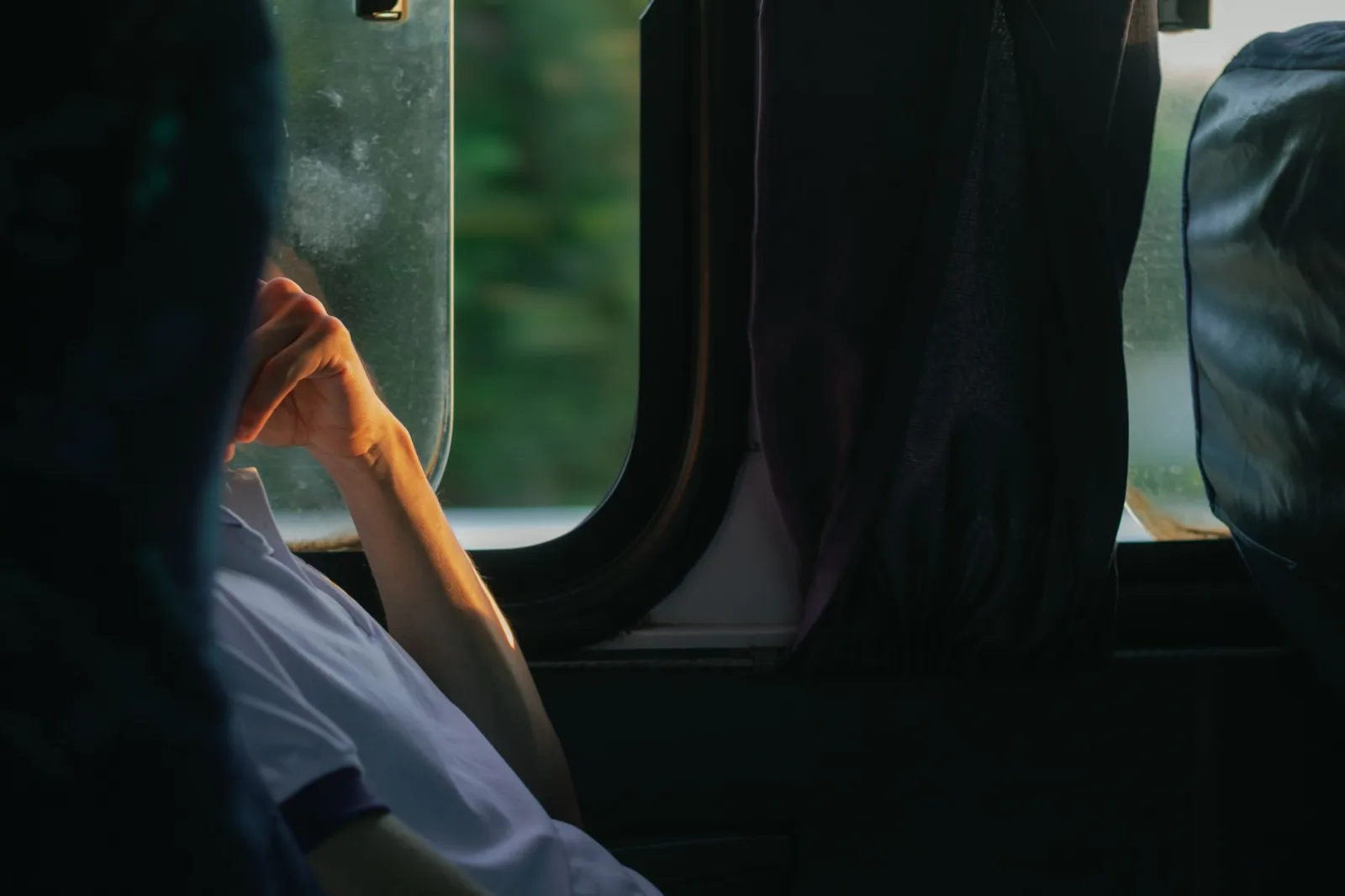 A man sitting pensively on a bus, gazing out the window during daytime travel in Paudalho, Brazil.